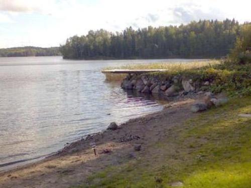 a beach with a body of water and trees at Holiday Home Karri by Interhome in Tallnäs