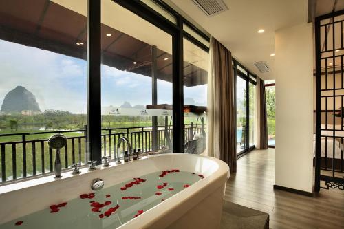 una vasca da bagno in una stanza con una grande finestra di Peach Blossom Resort Hotel a Guilin