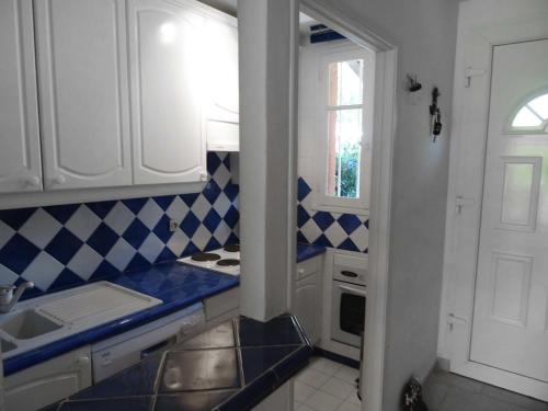 コゴランにあるHoliday Home Les Mas de Cogolin by Interhomeの白いキャビネットと青と白のタイルが備わるキッチン