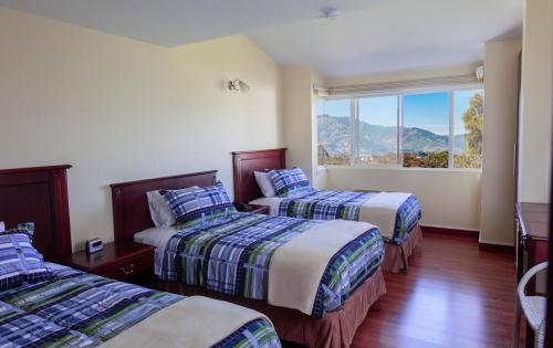 a hotel room with two beds and a window at Hotel Casa Sayu in Tumbaco