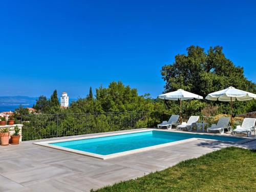 a swimming pool with chairs and umbrellas at Apartment Villa Tara-2 by Interhome in Brseč