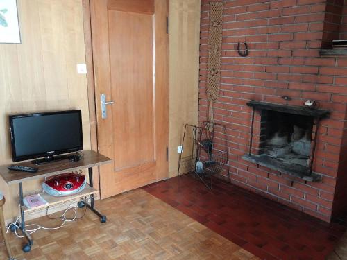 een woonkamer met een stenen open haard en een televisie bij Apartment Steinacher by Interhome in Engelberg