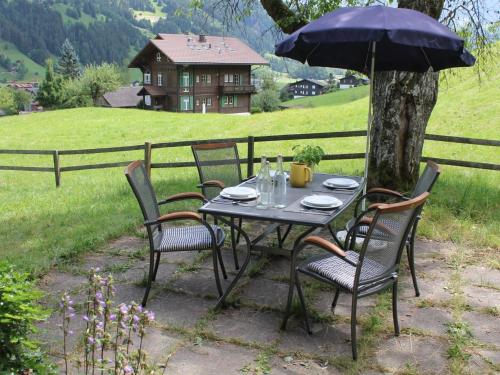 a table with chairs and an umbrella in front of a fence at Apartment Chalet Maru by Interhome in Lenk