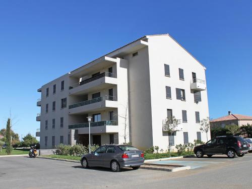 un bâtiment blanc avec deux voitures garées dans un parking dans l'établissement Apartment Lup - Les terrasses d'Alistro by Interhome, à San-Giuliano