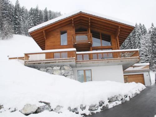 una cabaña de madera en la nieve con entrada en Apartment Nubes- Chalet by Interhome, en Zweisimmen