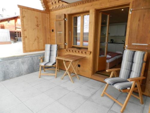 eine Terrasse mit 2 Stühlen, einem Tisch und einer Küche in der Unterkunft Apartment Mutthorn by Interhome in Lauenen