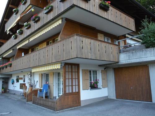 a building with a balcony with a blue chair in front of it at Apartment Eichhorn by Interhome in Zweisimmen