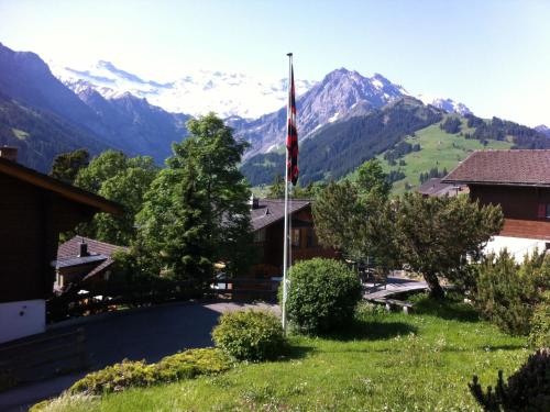 a house with a flag and mountains in the background at Apartment Krebs by Interhome in Adelboden