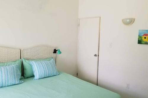 a bed with blue pillows in a white bedroom at Breathtaking View - Playa Lagun - Curacao in Lagun