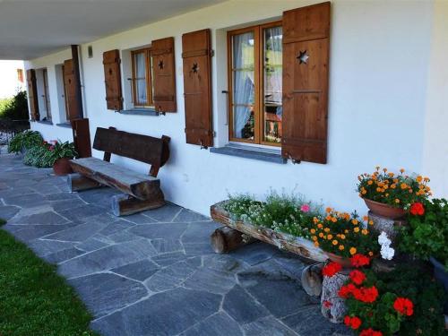 a house with a bench and flowers in front of it at Apartment Alegria - Parterre by Interhome in Gstaad
