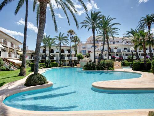 a swimming pool with palm trees in front of a building at Apartment Bahia Azul in Denia