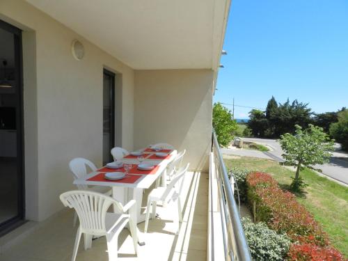 d'un balcon avec une table et des chaises blanches. dans l'établissement Apartment Lup - Les terrasses d'Alistro by Interhome, à San-Giuliano
