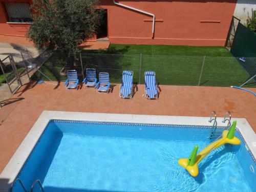 una piscina con sillas y un fideo en ella en Apartamentos Turísticos Domus Aquae, en Mérida