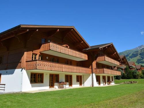 a large building with a wooden roof on a field at Apartment Jacqueline 24 by Interhome in Gstaad