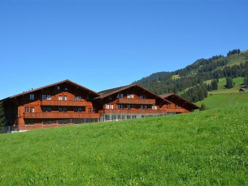 een groot houten gebouw op de top van een groene heuvel bij Apartment Mireille Nr- 3 by Interhome in Gstaad