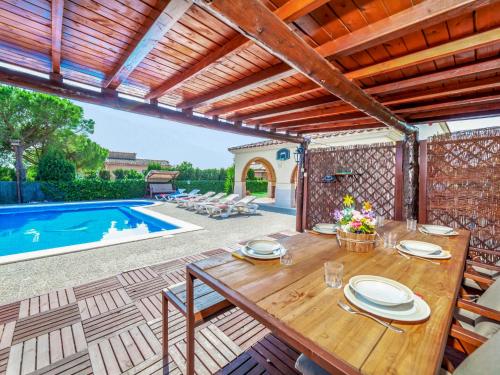 un patio con una mesa de madera y una piscina en Holiday Home Mari by Interhome, en Sant Antoni de Calonge