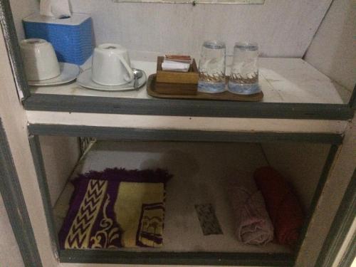 a shelf with two glasses and plates on it at Roemah Abdoe in Arau