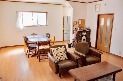 een woonkamer met een tafel en stoelen en een bank bij Farm Stay Ichirobee in Fukui