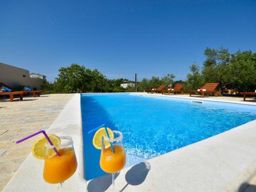 two glasses of orange juice sitting next to a swimming pool at Apartment Jasminka-1 by Interhome in Drage