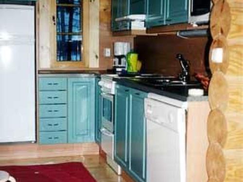 una cocina con armarios azules y electrodomésticos blancos en Holiday Home Niemennokka by Interhome, en Kammola