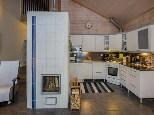 a kitchen with white cabinets and a fireplace at Holiday Home Koliwood a by Interhome in Kolinkylä