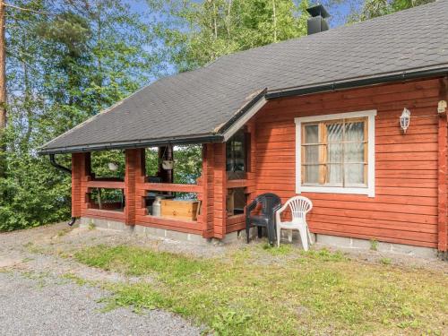 Cabaña de madera con porche y 2 sillas blancas en Holiday Home Tallukka by Interhome, en Pertunmaa