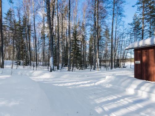 un patio cubierto de nieve con un cobertizo y árboles en Holiday Home 2234 by Interhome, en Savonranta