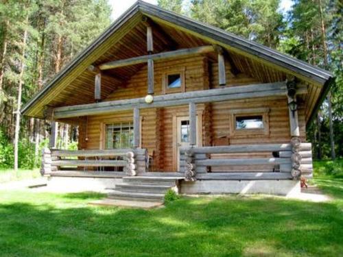 a log cabin with a porch and stairs in the grass at Holiday Home 6309 by Interhome in Konginkangas