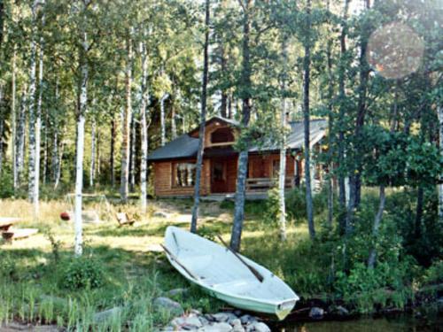 a boat sitting in the grass in front of a cabin at Holiday Home Hepolehto by Interhome in Säkinmäki
