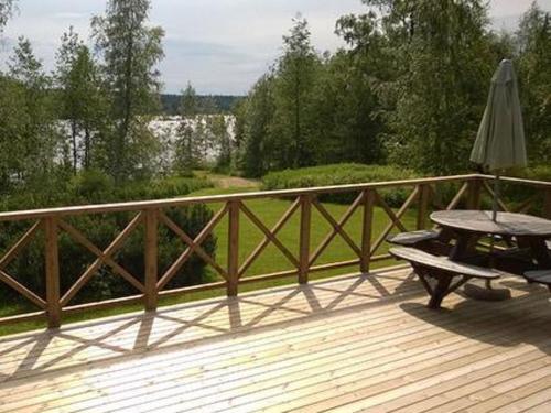 eine Holzterrasse mit einem Tisch und einem Sonnenschirm in der Unterkunft Holiday Home 5650 by Interhome in Koskenpää