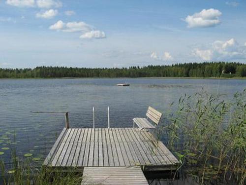 einem Holzsteg mit einer Bank auf einem See in der Unterkunft Holiday Home Käpälämäki by Interhome in Lahdenkylä