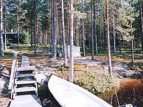 un barco sentado junto a un puente en un bosque en Holiday Home Aittoniemi i by Interhome, en Hopsu