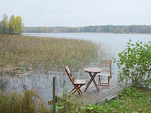 HaraにあるHoliday Home Eteläranta by Interhomeの湖の桟橋に座るテーブルと椅子2脚