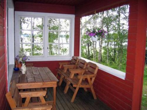 um alpendre com uma mesa e cadeiras de madeira e 2 janelas em Holiday Home Pihlajatupa by Interhome em Kittilä