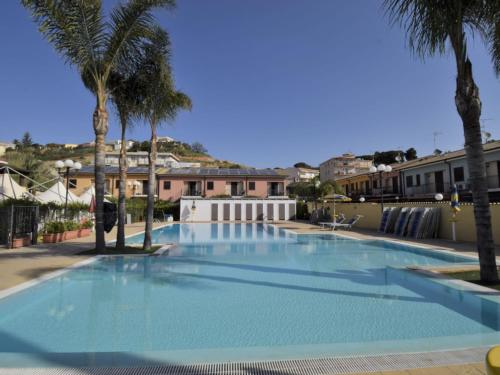 Una gran piscina azul con palmeras y edificios. en Apartment L'Ancora-1 by Interhome, en Porto Empedocle