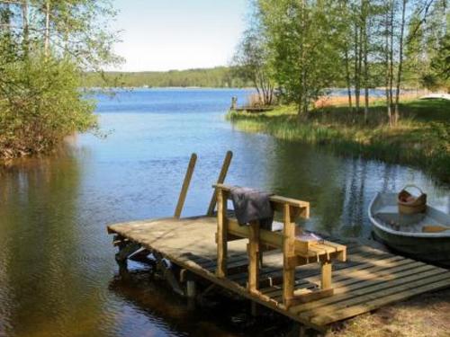 einen Stuhl auf einem Steg mit einem Boot auf einem See in der Unterkunft Holiday Home Metsäpirtti by Interhome in Pätiälä