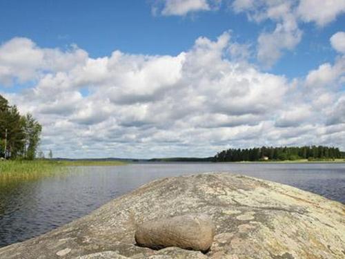 a large rock sitting on the shore of a lake at Holiday Home Divaanikivi by Interhome in Pätiälä