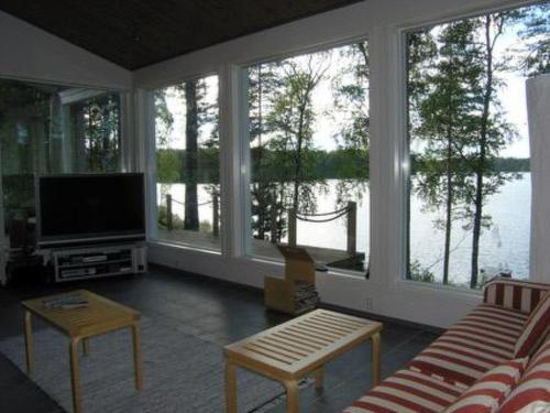 a living room with a television and large windows at Holiday Home Harjunniemi by Interhome in Vilppula