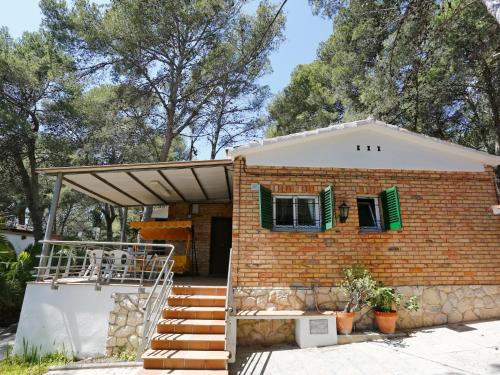 サロウにあるHoliday Home Penya Tallada by Interhomeの緑のシャッター付き窓と階段のあるレンガ造りの家