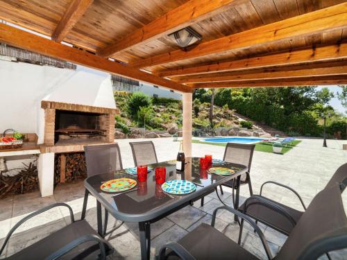 un patio con mesa, sillas y chimenea en Holiday Home Irisada by Interhome en Fogás de Tordera