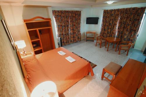 1 dormitorio con 1 cama de color naranja, mesa y sillas en HOTEL EL CONQUISTADOR MONARCA., en Zitácuaro