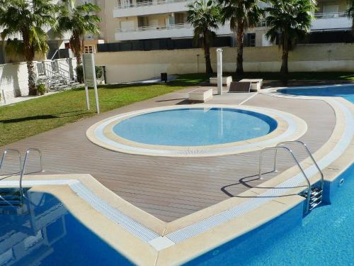 una piscina con terrazza in legno accanto a un edificio di Apartment Elegance Plus-1 by Interhome a Denia