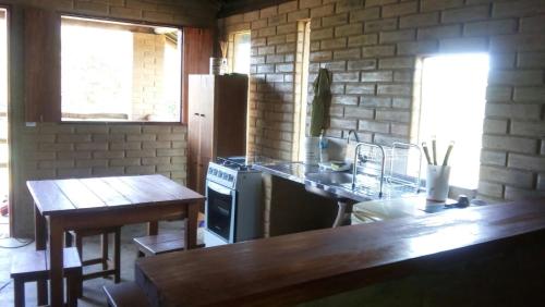 a kitchen with a counter and a table and a refrigerator at Pousada Morro da Baleia in Alto Paraíso de Goiás