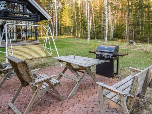 een picknicktafel en twee stoelen naast een grill bij Holiday Home Leporanta by Interhome in Herttuala