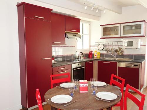 une cuisine avec une table en bois et des chaises rouges dans l'établissement Holiday Home La Rodière by Interhome, à Saint-Lunaire