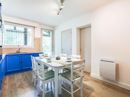 une cuisine avec des placards bleus et une table et des chaises blanches dans l'établissement Holiday Home Mauriac by Interhome, à Soorts-Hossegor