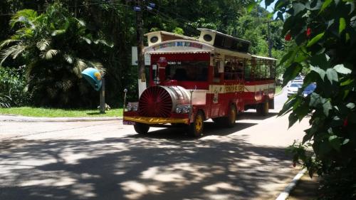 a red trolley car driving down a street at Pousada Bem Querer in Penedo