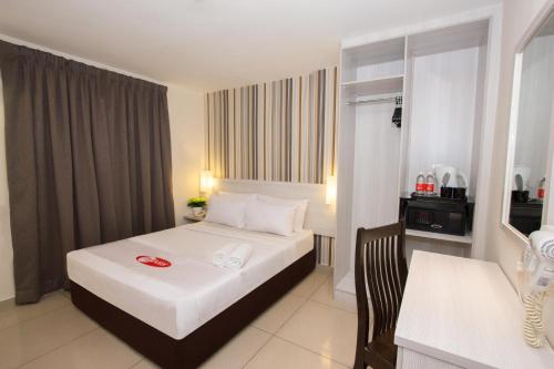 クアラルンプールにあるマイ ホテル @ セントラルの白いベッドとデスクが備わるホテルルームです。