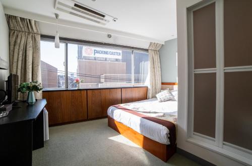 Tabata Oji Hotel في طوكيو: غرفة نوم بسرير ونافذة كبيرة