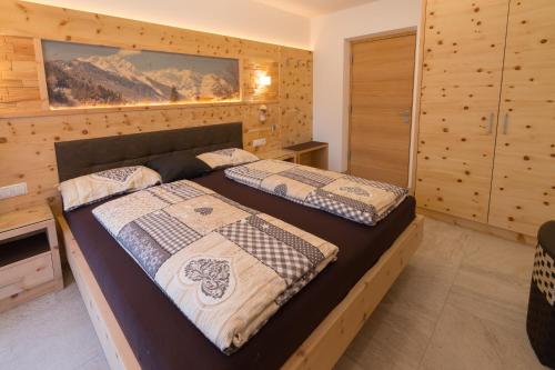 two beds in a bedroom with wooden walls at Chalet Schwarzenstein in Campo Tures